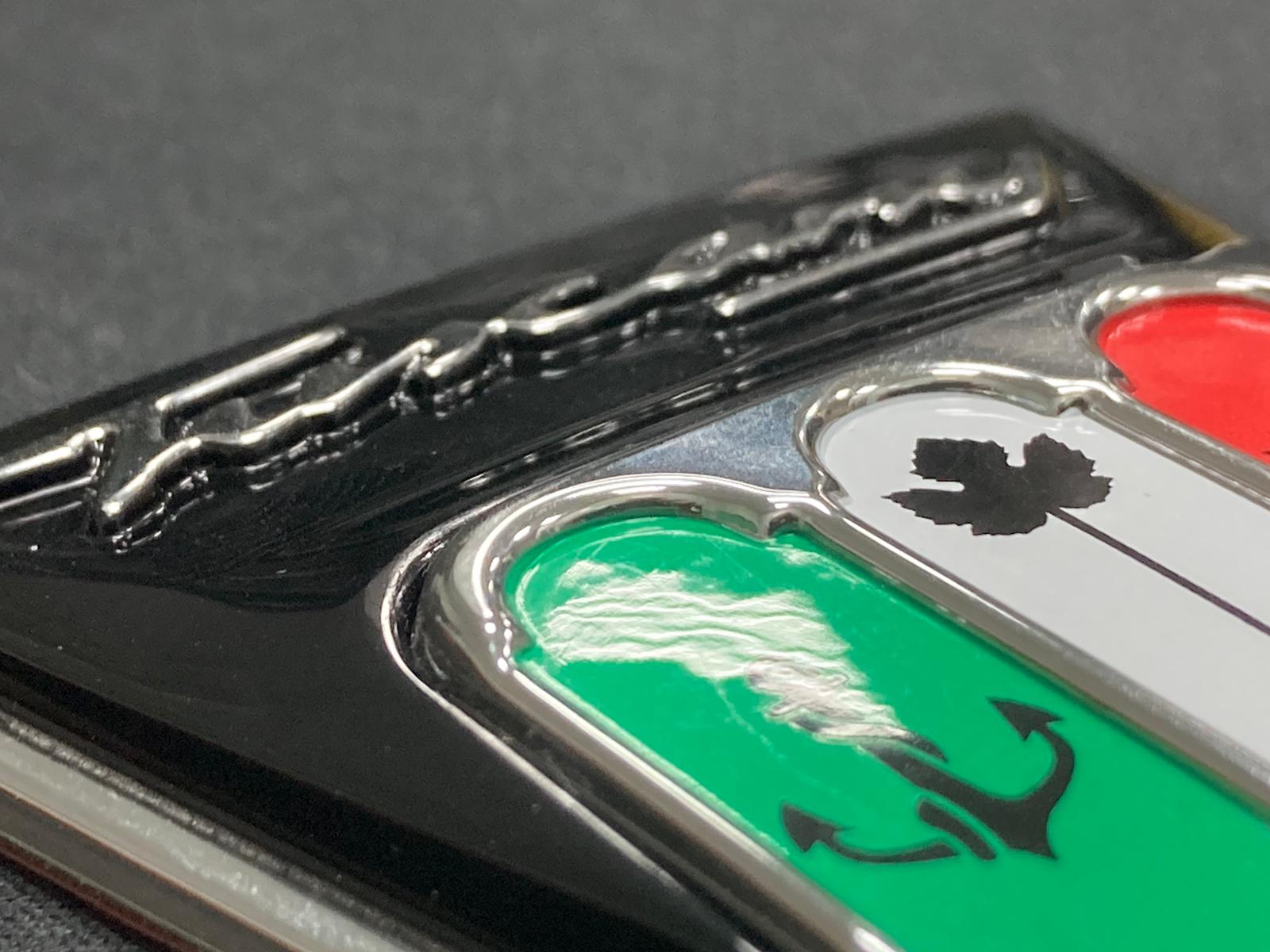 Injection molded badge with raised lettering and in-mold decoration