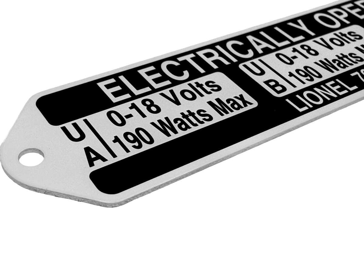 Close-up of a black and white industrial nameplate showing electrical rating specifications, including voltage and wattage