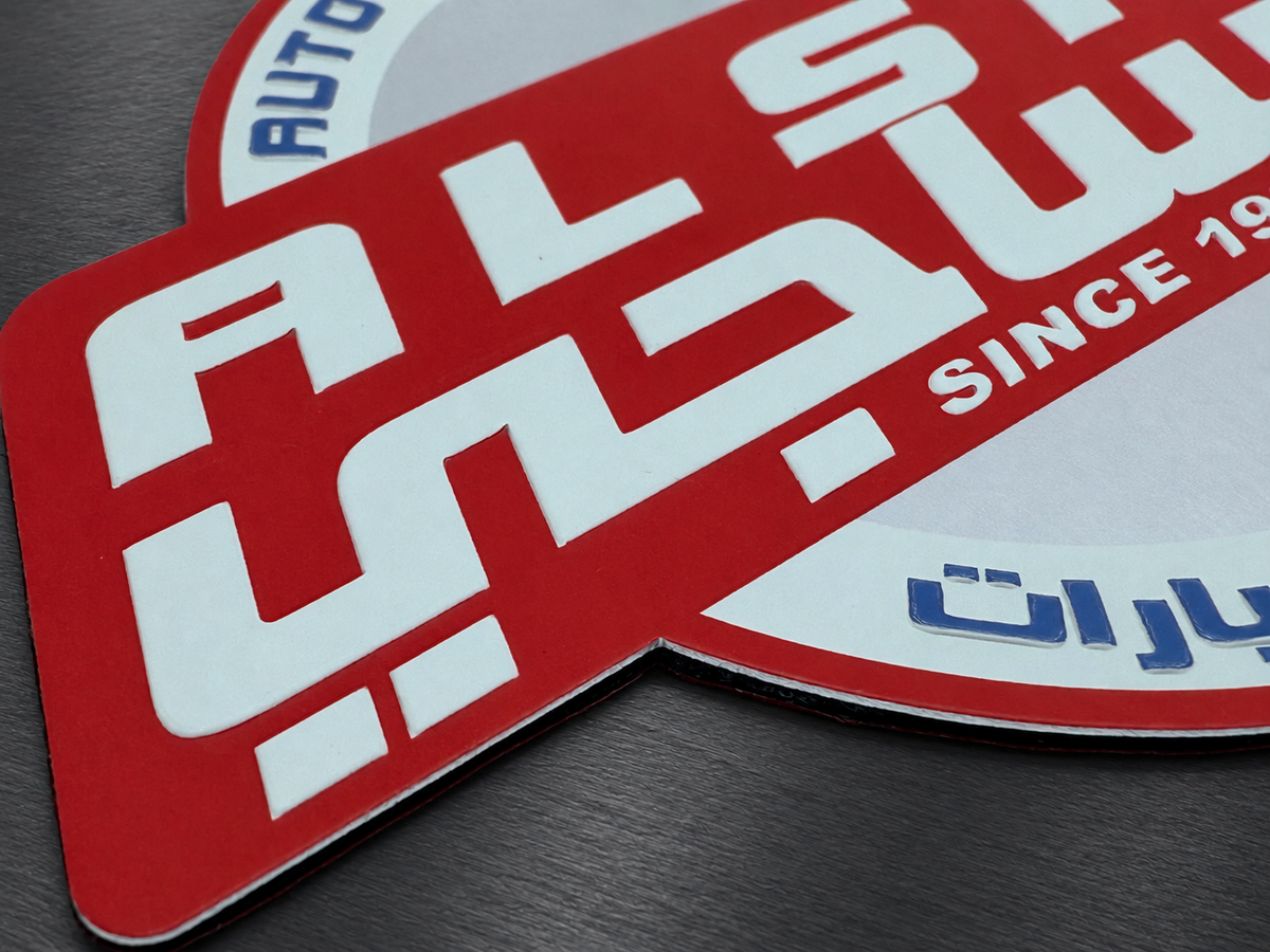 Close-up of a red, white, and blue aluminum badge showing printed graphics and surface finish.