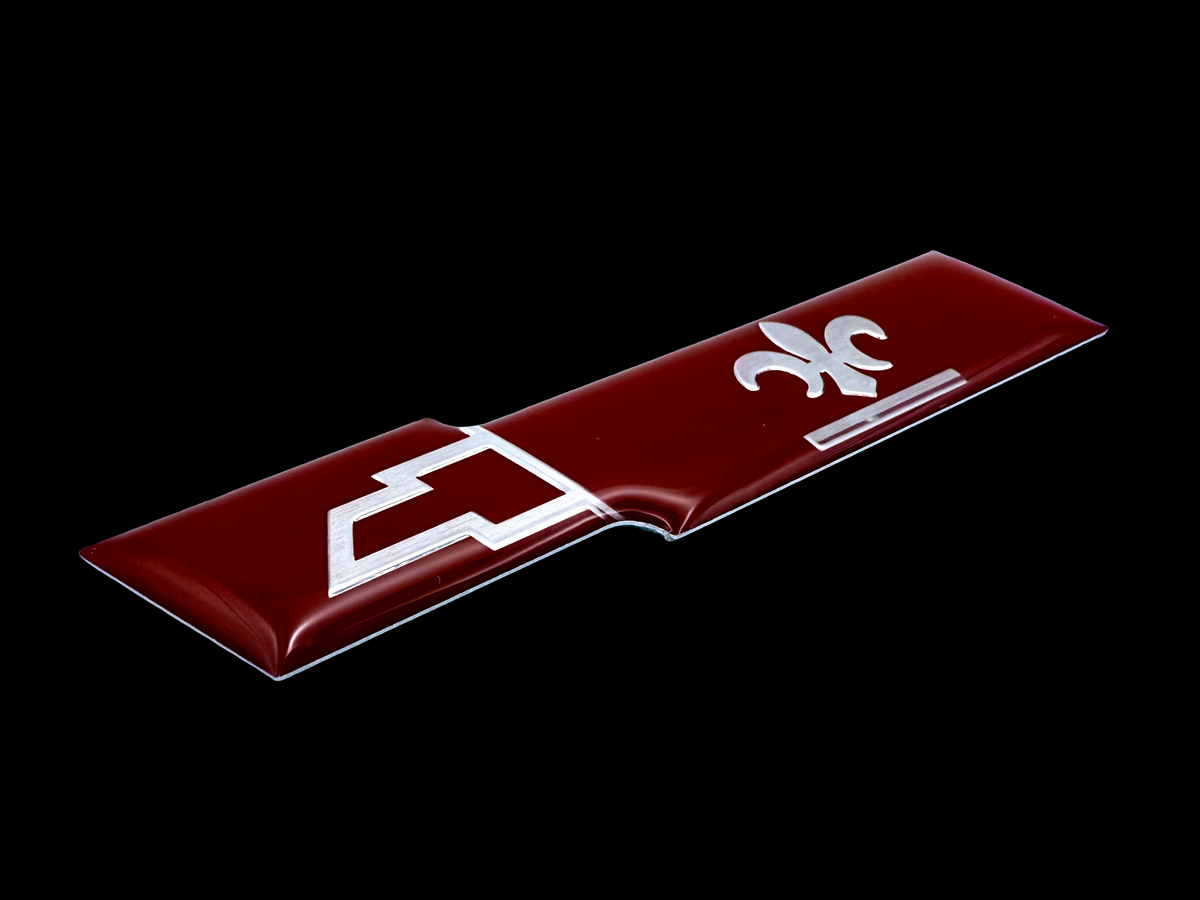 Chevy resin domed label made from aluminum with red screen printing, embossing and adhesive. 