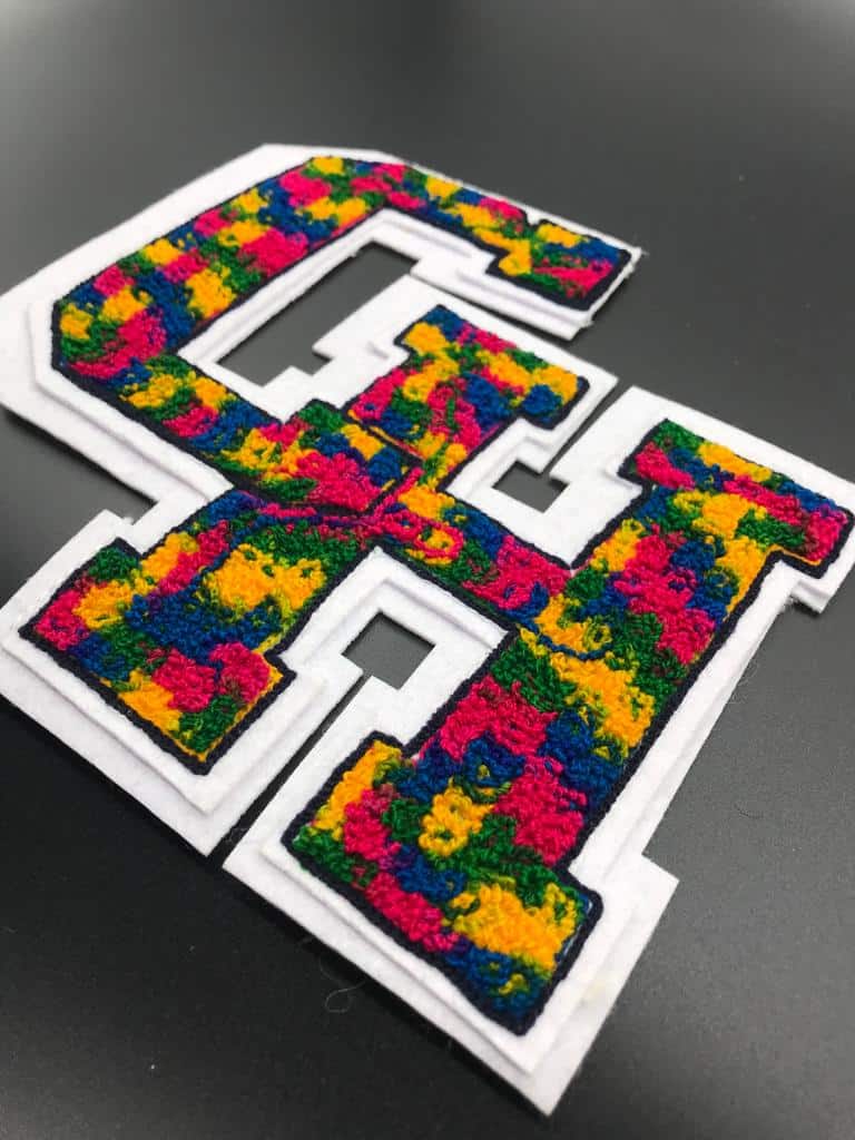 A colorful chenille patch of the letter CH