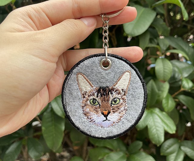 Silver embroidered keychain with a kitten on the frontside 