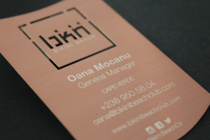 Beautifully designed brass business card with portions of the card's design being cut out and portions printed
