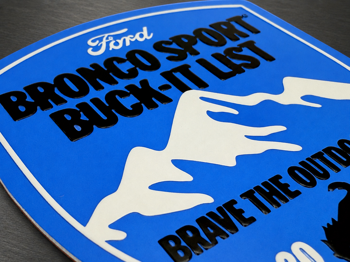 Custom blue metal badge with printed graphics and raised black lettering