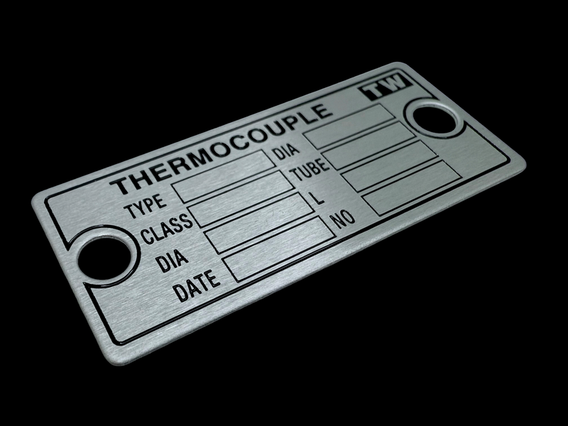 Etched stainless steel with black paint filling. Mounting holes on the left and right side. 