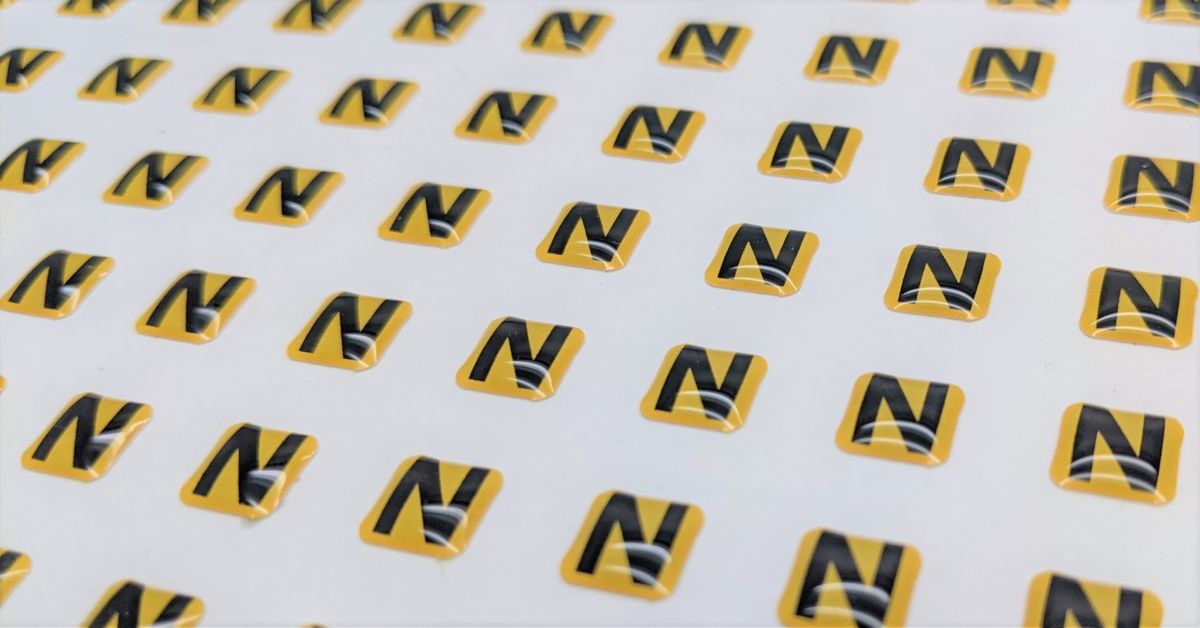 A sheet of yellow dome labels with a black screen printed N across the middle